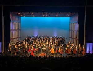 Kentucky Wesleyan Singers and the Owensboro Symphony Chorus stand behind the Owensboro Symphony Orchestra onstage during a performance
