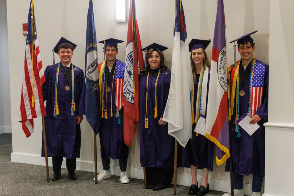 Top five graduates holding American, Kentucky, Owensboro, Christian, and Kentucky Wesleyan flags
