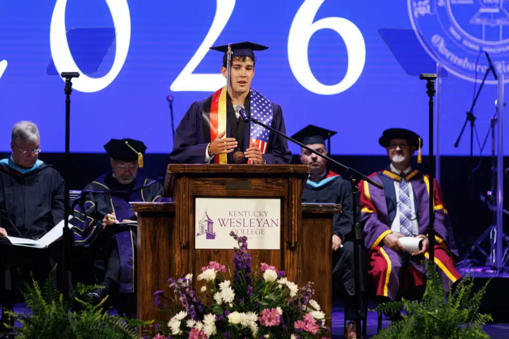 Valedictorian delivering address at commencement podium.