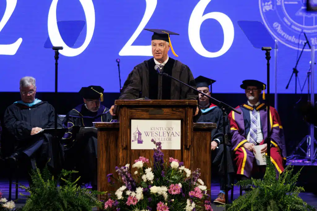 Honorary graduate Keith Sharber delivering commencement speech at podium.