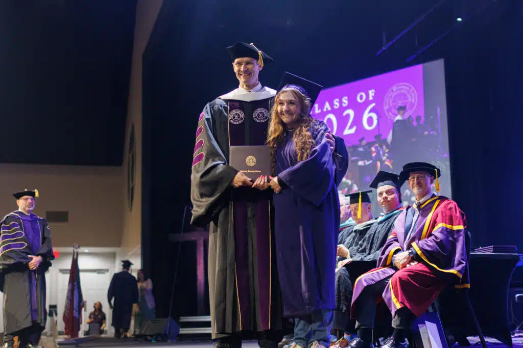 President Cousins presenting a diploma to a graduate at Commencement.