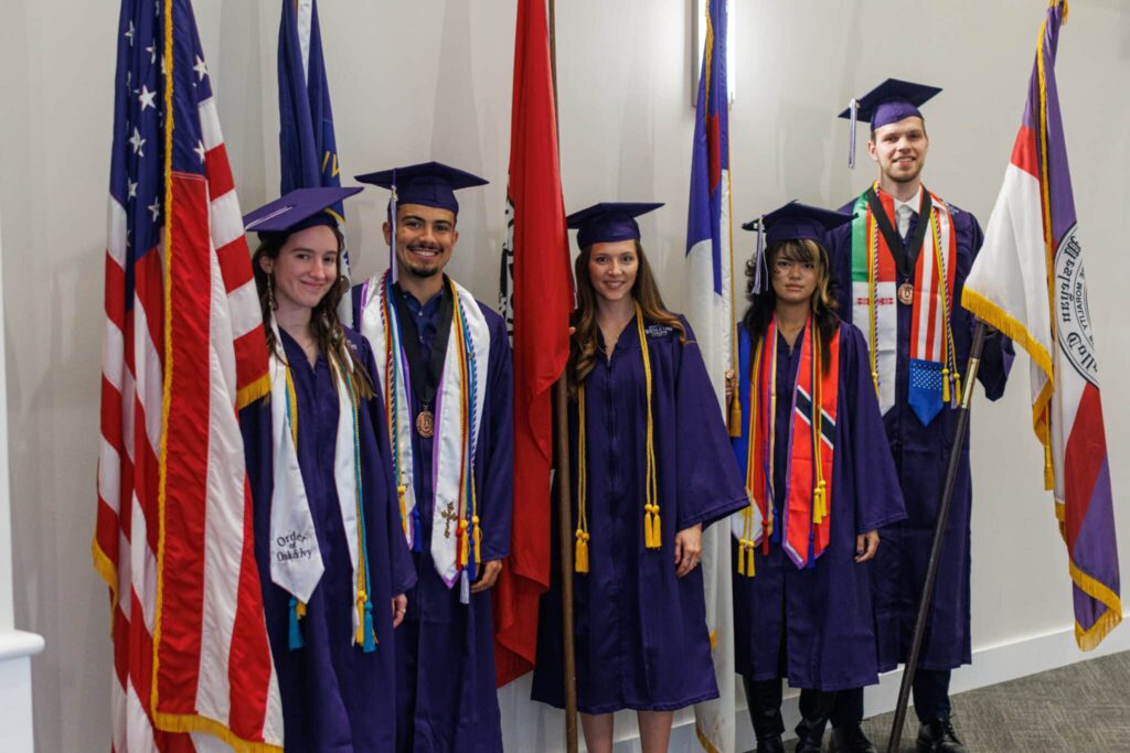 The top 5 students of the graduating class hold flags as they prepare to enter the ceremony.