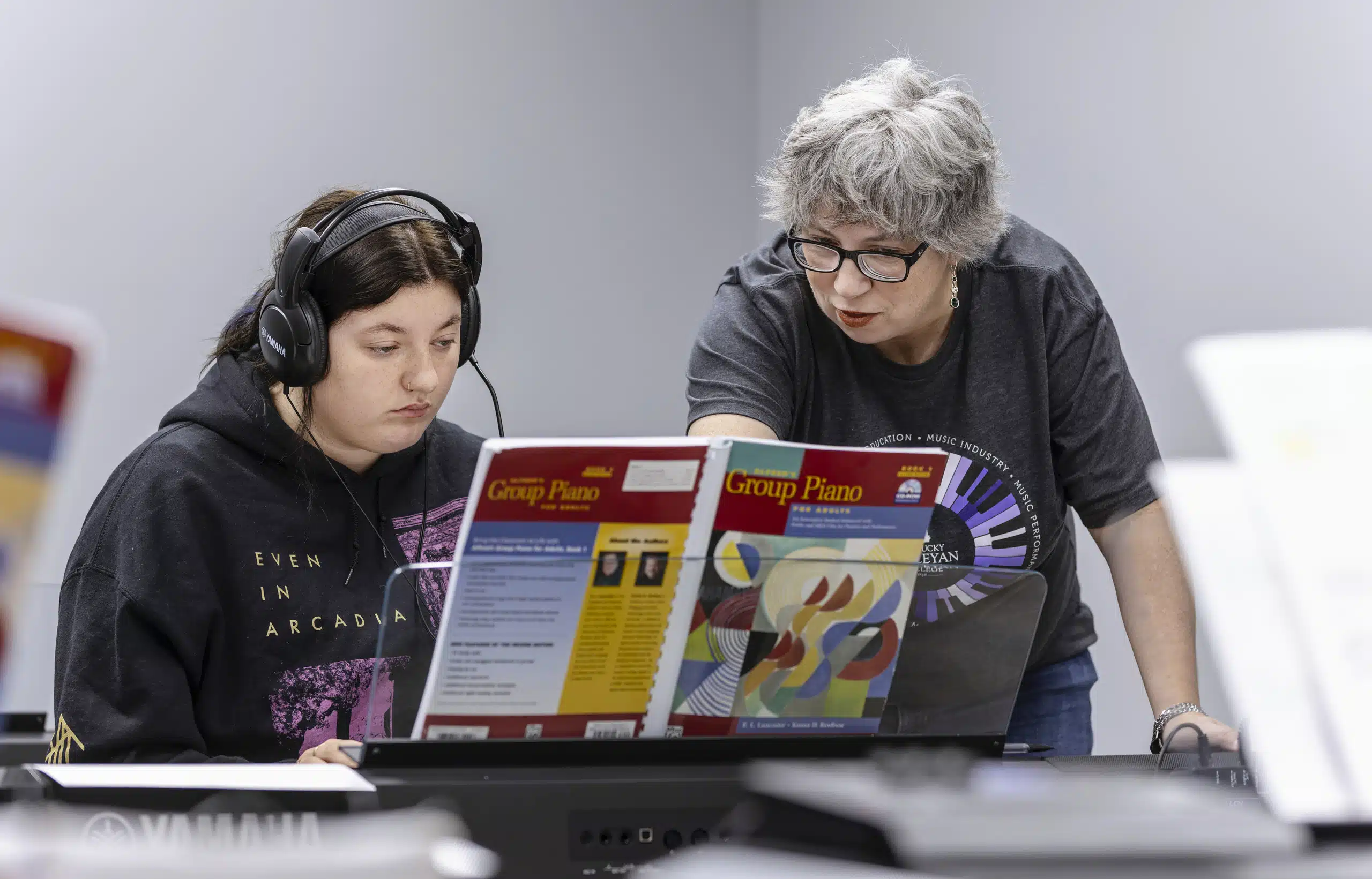 A music professor engaging with a student in the music studio room