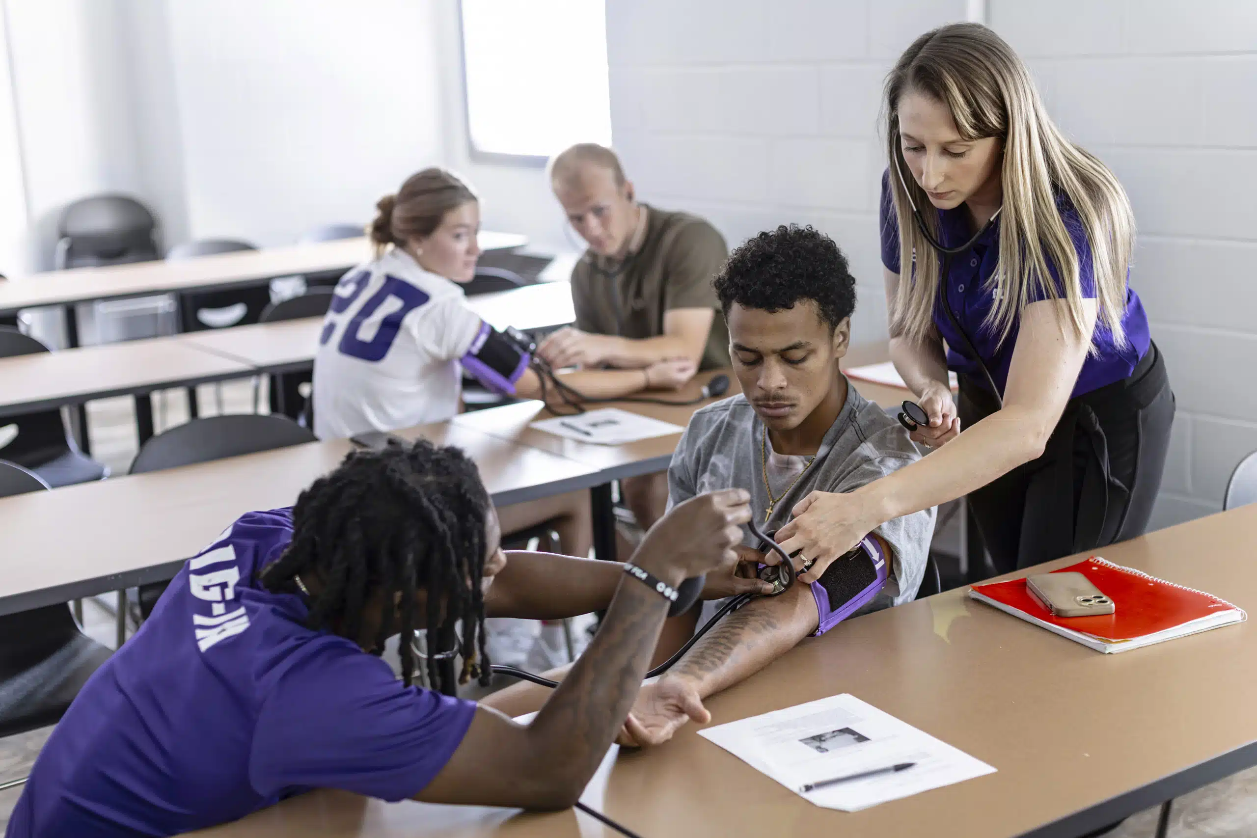 Health care students practicing taking blood pressure readings on other students