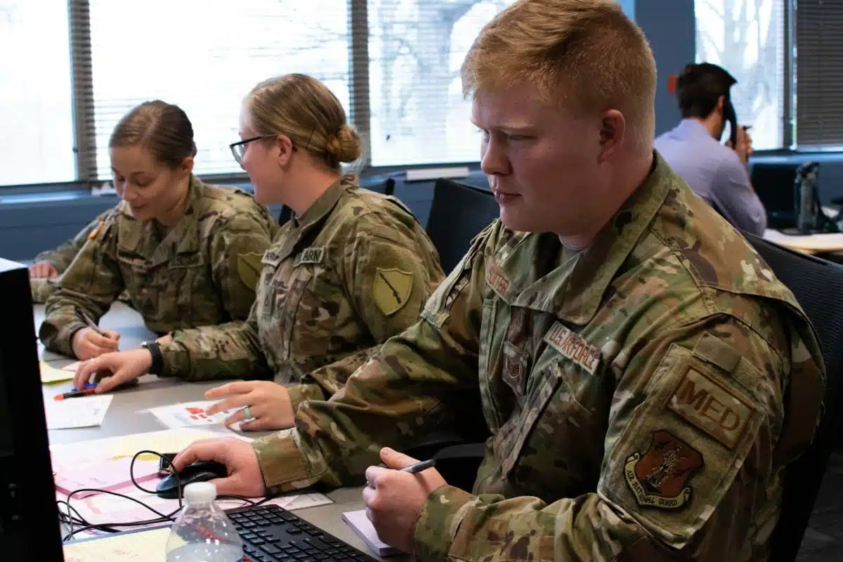 Three National Guard students working together at a desk