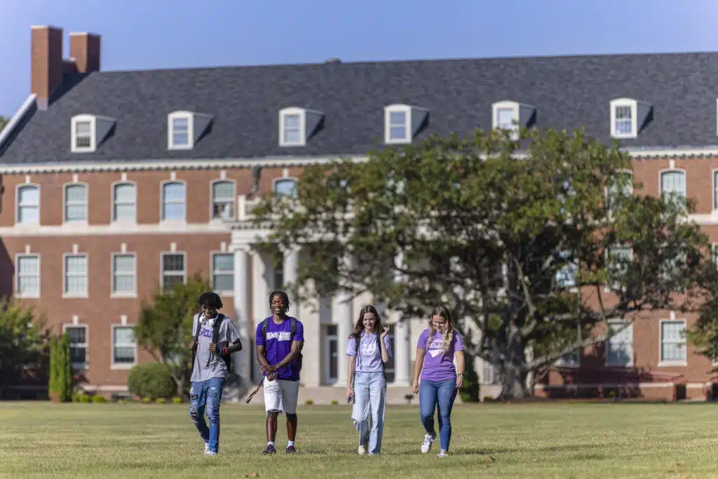 Four students walking in the front lawn on campus