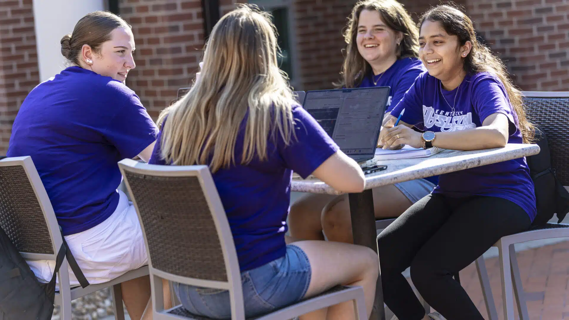 Students sitting at an outdoor table on campus