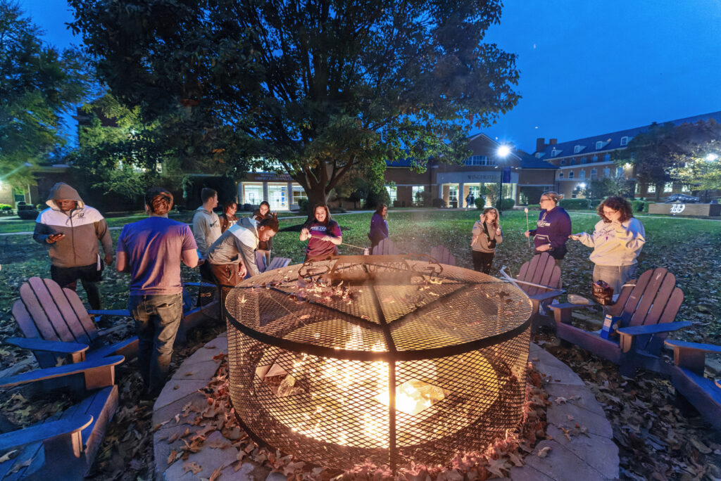 students gather by firepit outside Winchester Center