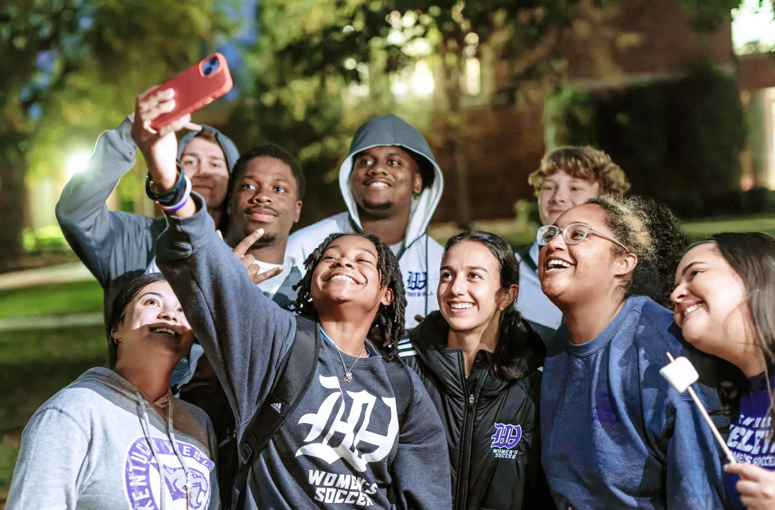 Group of students taking a selfie outside on campus at nighttime