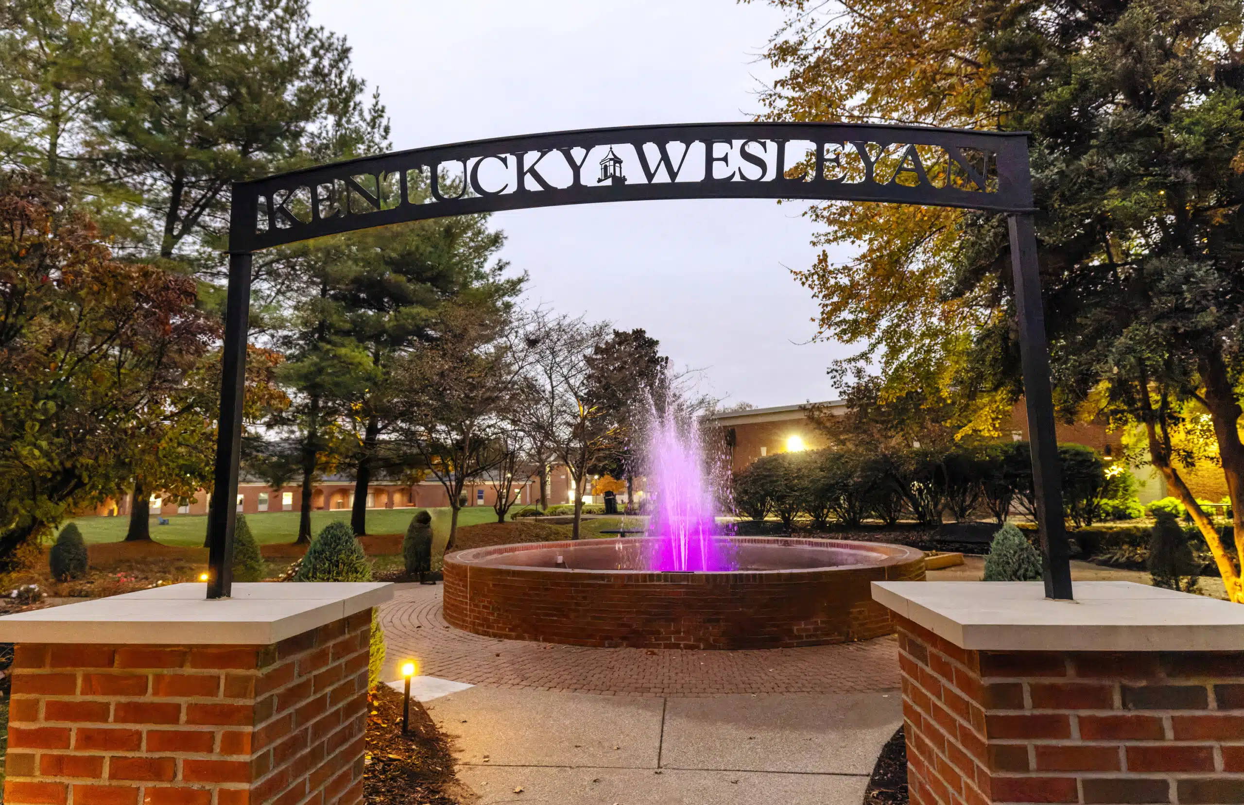 fountain on campus with archway and purple uplighting