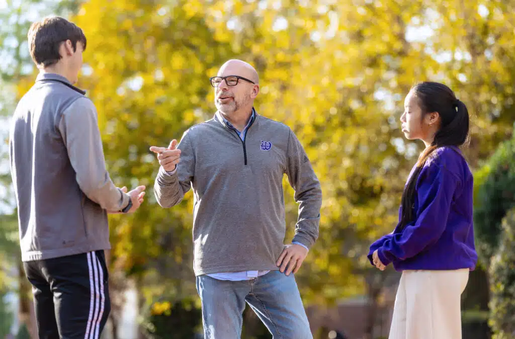 Professor talking to students outside on campus