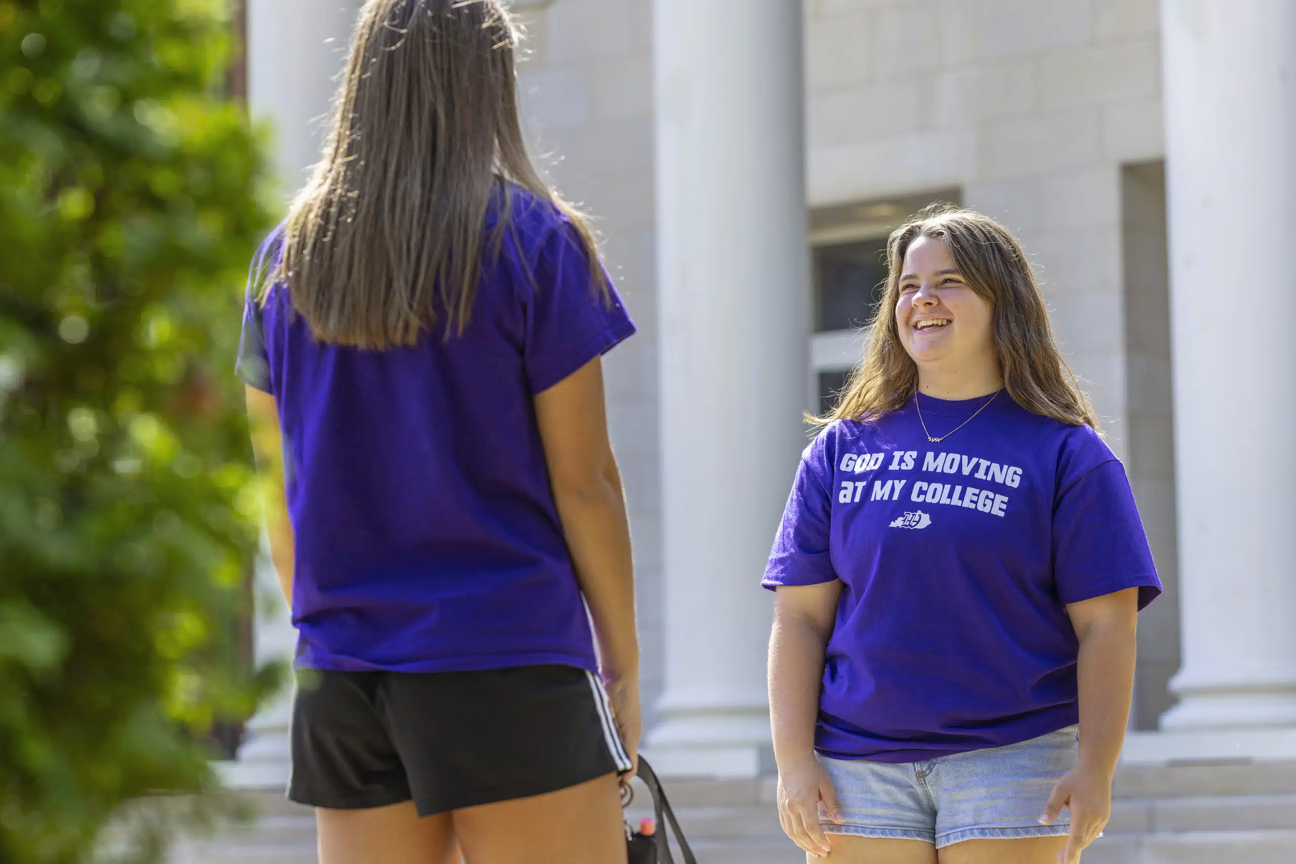 Two students in conversation in front of the large columns on campus