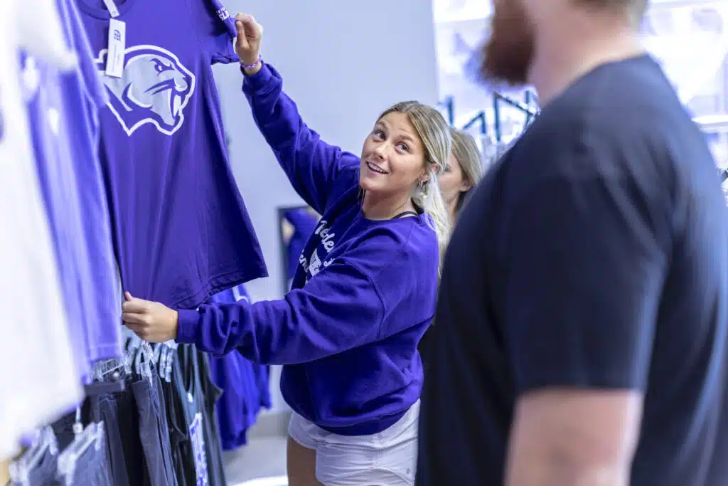 A student showing off a merchandise item inside the Panther Den Spirit Store on campus