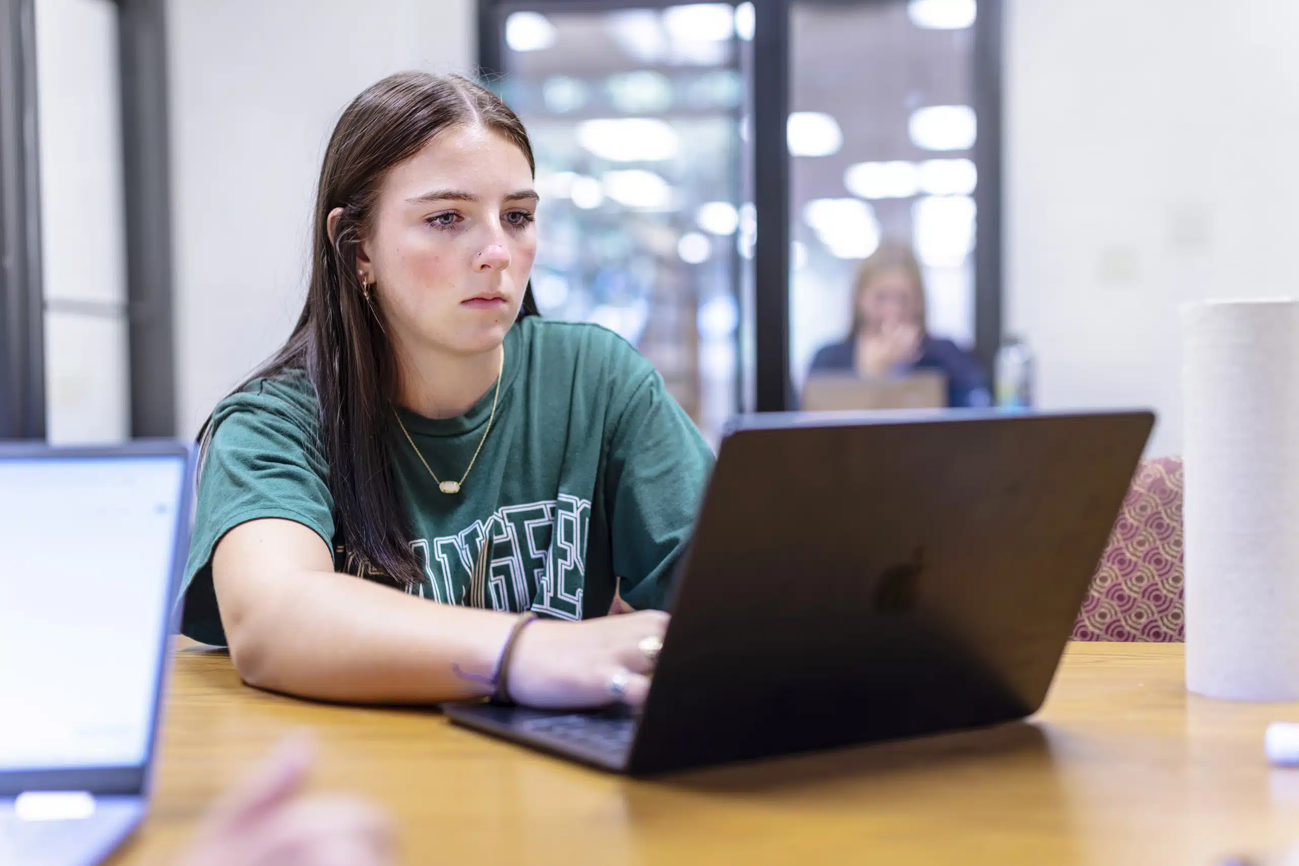 A student working intently on their laptop inside the KWC library