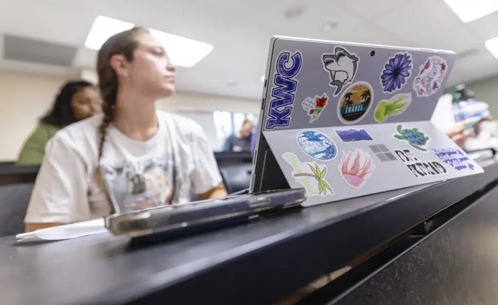 Student sitting behind laptop while engaged in lecture inside a classroom