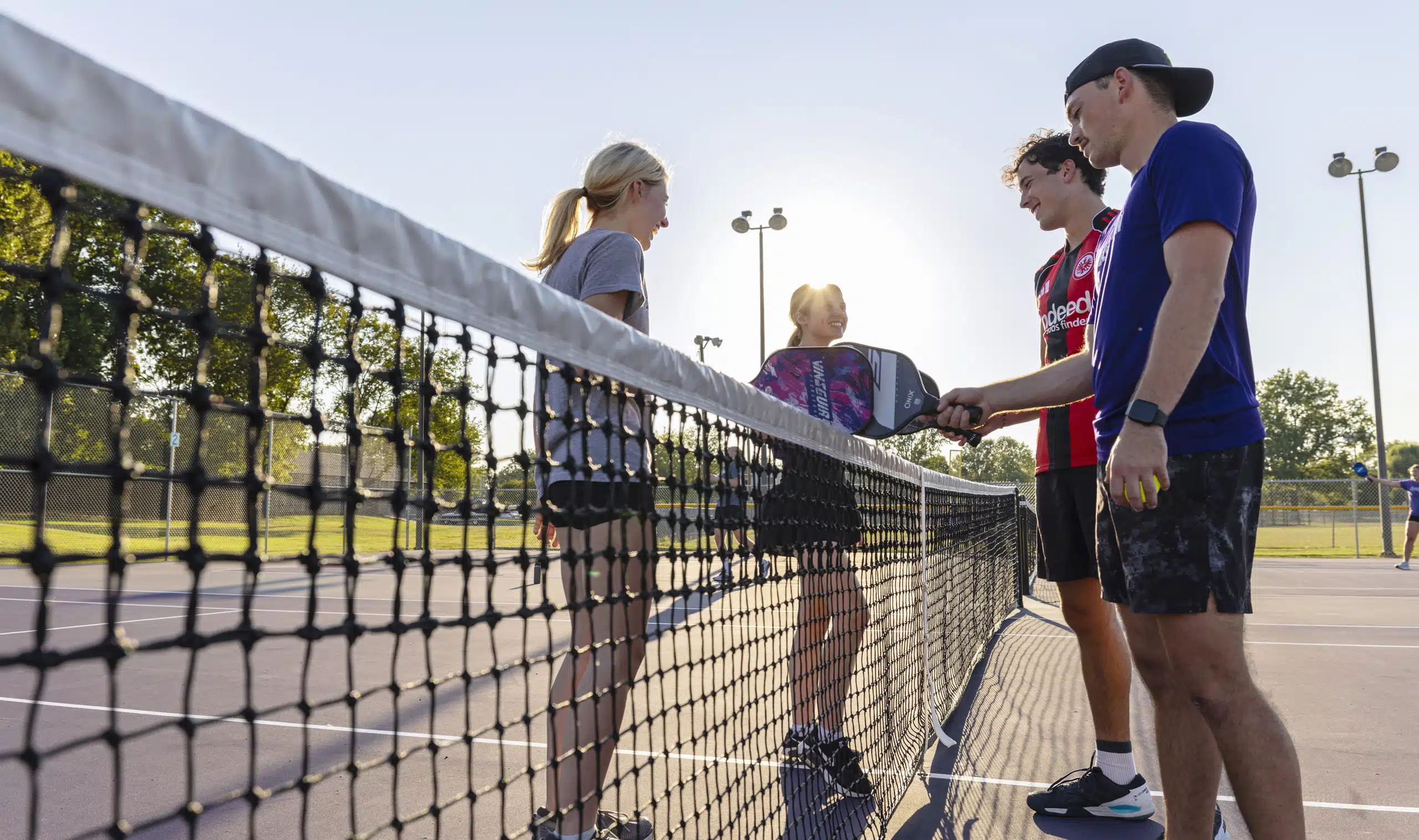 Four students huddling together during pickleball tournament