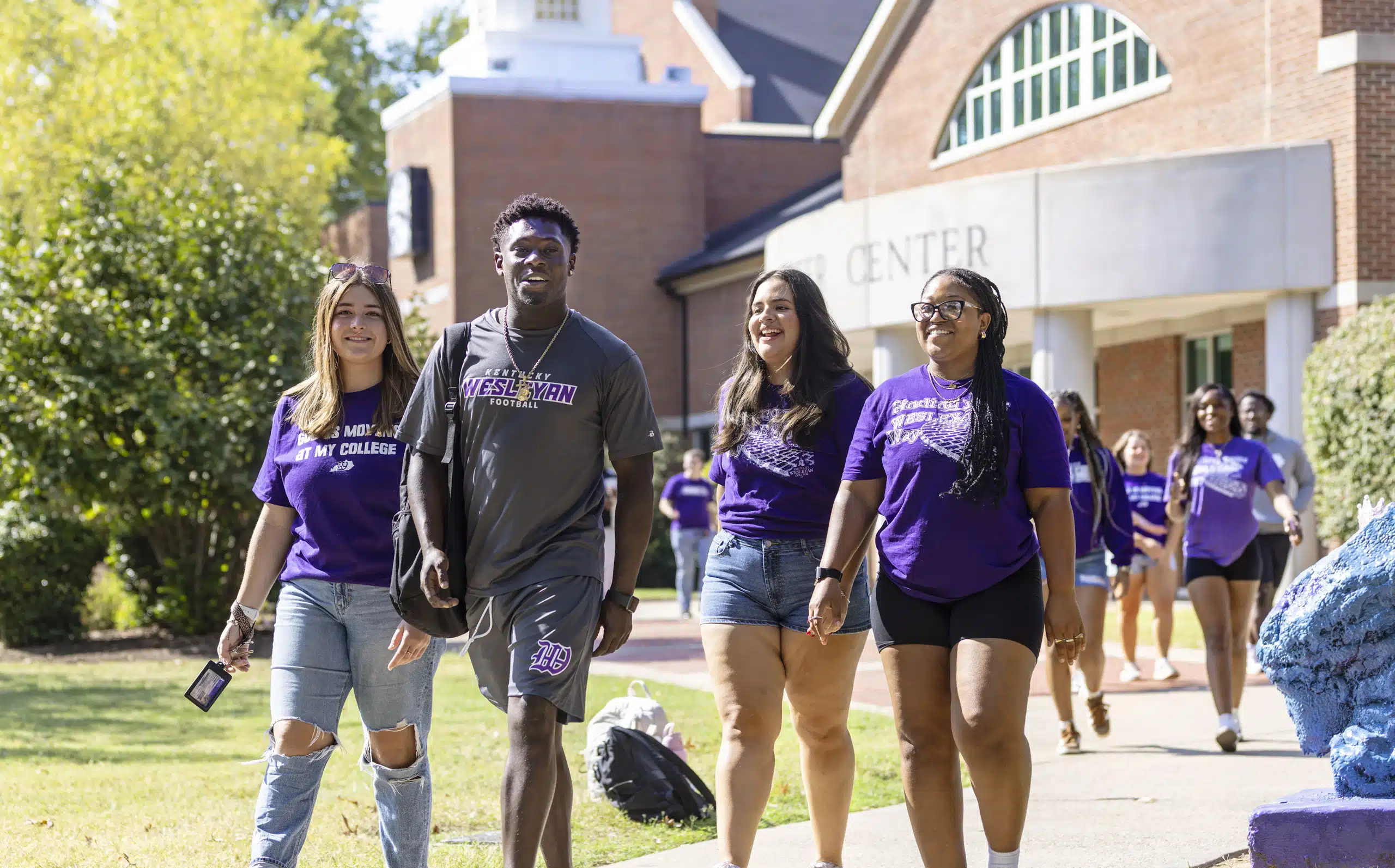 A group of students walking on the sidewalk outside the Winchester Center on campus