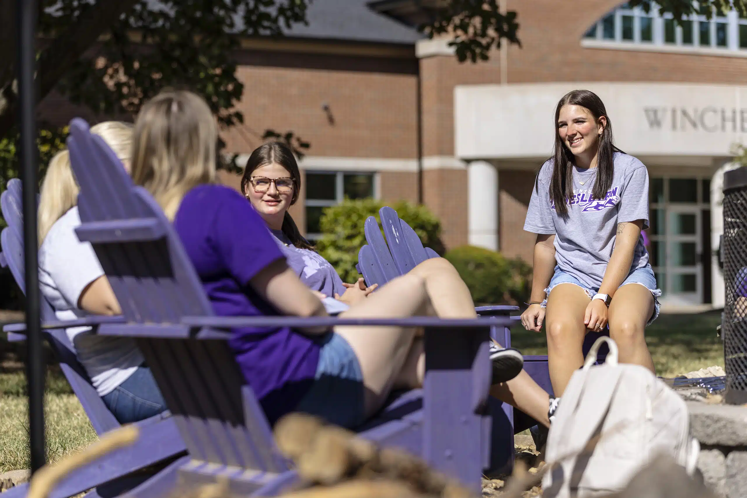 Students enjoying the outdoor purple chairs on campus